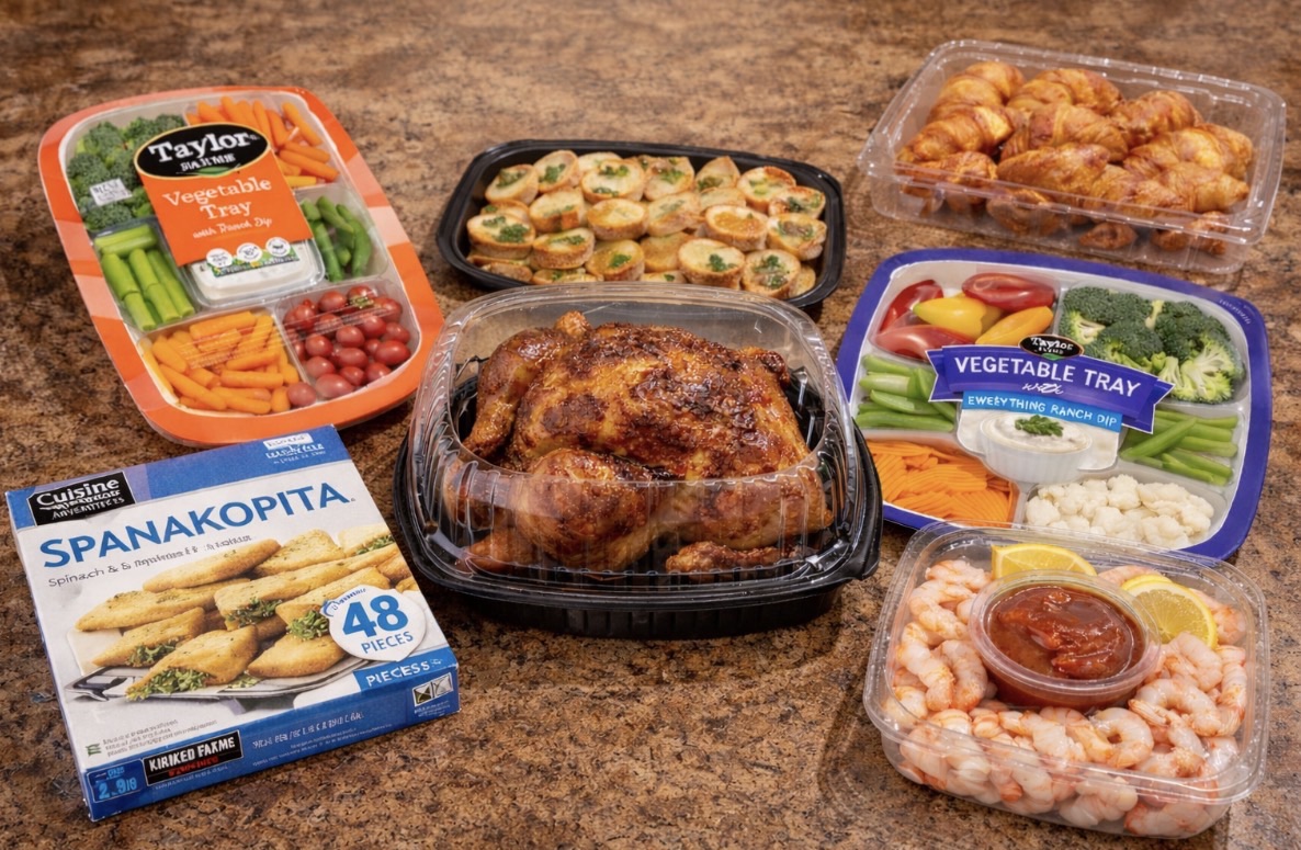 Costco graduation party food spread including spanakopita, rotisserie chicken, shrimp cocktail platter, vegetable tray, mini quiches, and butter croissants