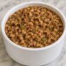 Bowl of Hoppin' John black-eyed peas served over rice with crispy bacon on top, a Southern New Year's Day tradition