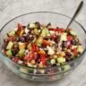 Mediterranean dense bean salad with cannellini beans, chickpeas, cucumber, tomato, kalamata olives, and feta in a lemon-oregano dressing