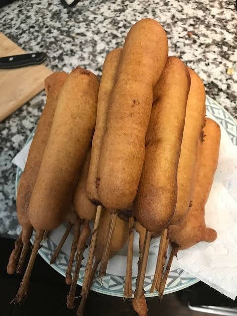 Homemade corn dogs on skewers, coated in cornmeal batter
