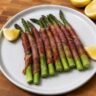 Roasted asparagus spears wrapped in crispy prosciutto on a baking sheet