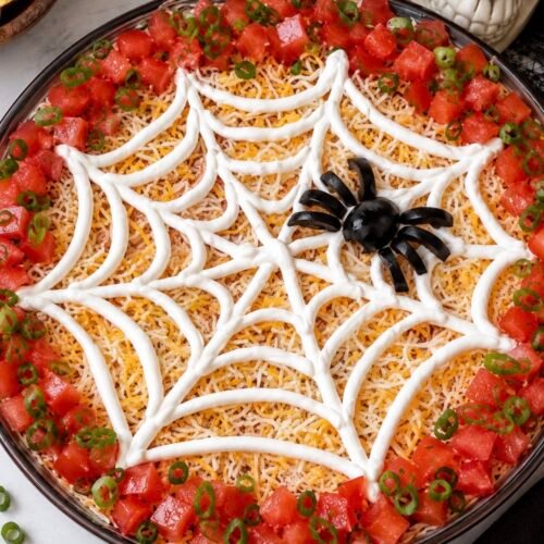Seven-layer Halloween dip topped with a sour cream spiderweb design