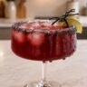 Pitcher of green Halloween batch margarita with salt-rimmed glasses and lime wheel garnish
